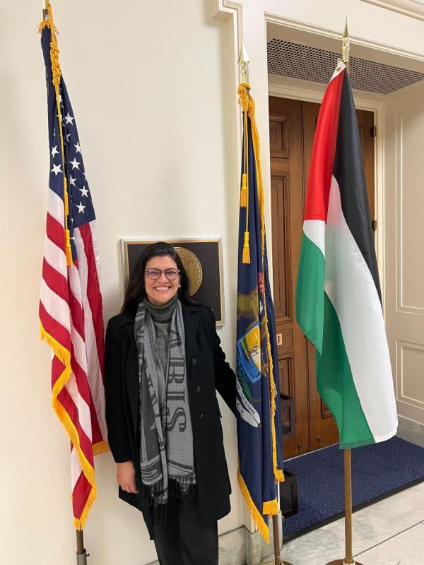 Tlaib poses with a Palestinian flag outside her office